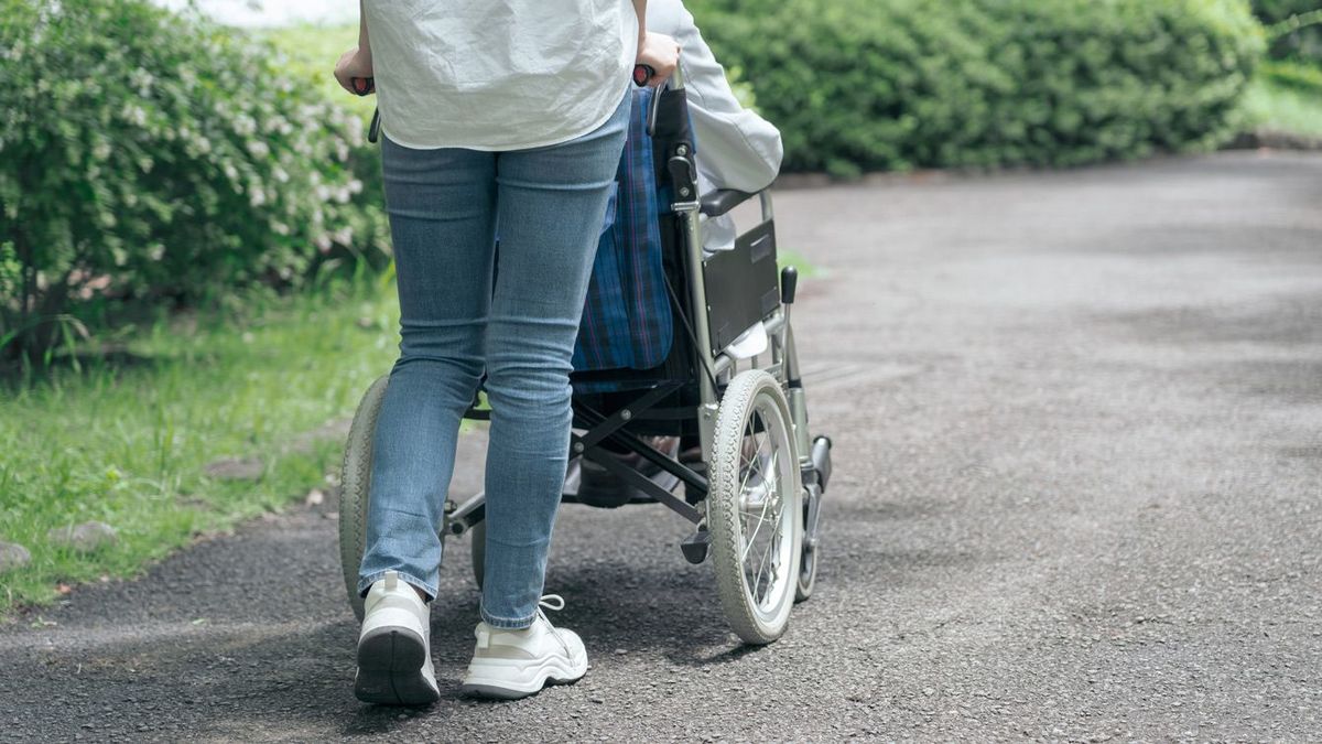 公園で車椅子を押して歩く若い女性