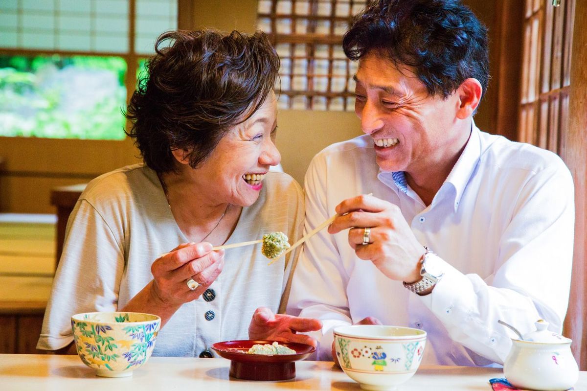 京都庭園のレストランでお気に入りをシェアして笑うシニア日本人カップル