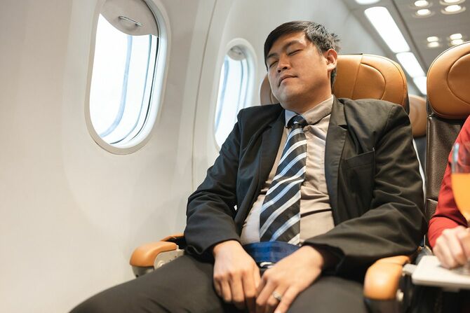 飛行機の中で寝るビジネスマン