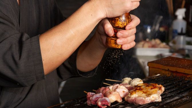焼き鳥に調味料をかける店主