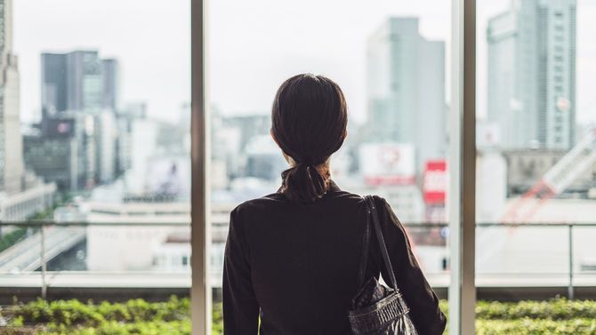 大都市で窓の外を見つめる女性