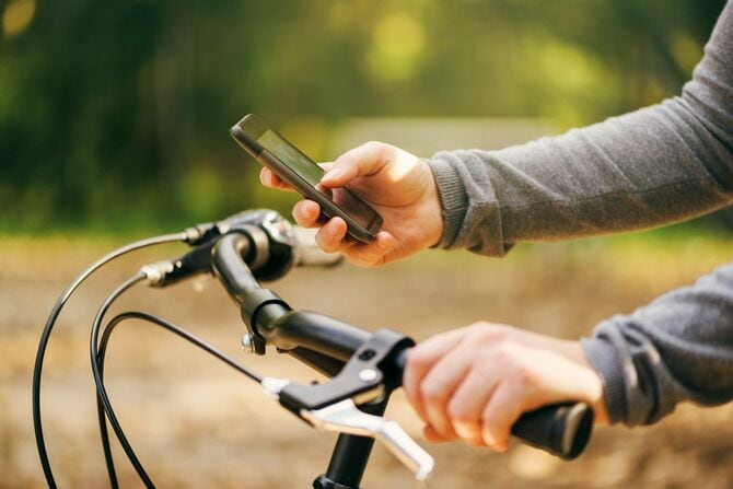 自転車に乗りながらスマホを使用している男性の手元