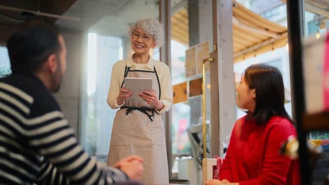 カフェレストランで客から注文を受ける働く年配の女性