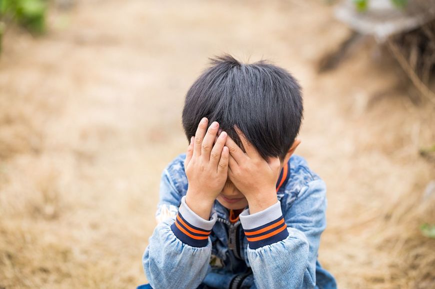 手で顔を覆って泣く子ども