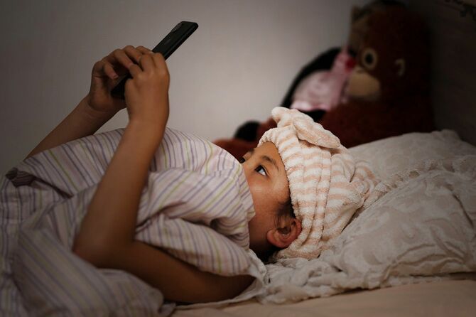 ベッドでスマートフォンを使用する女の子