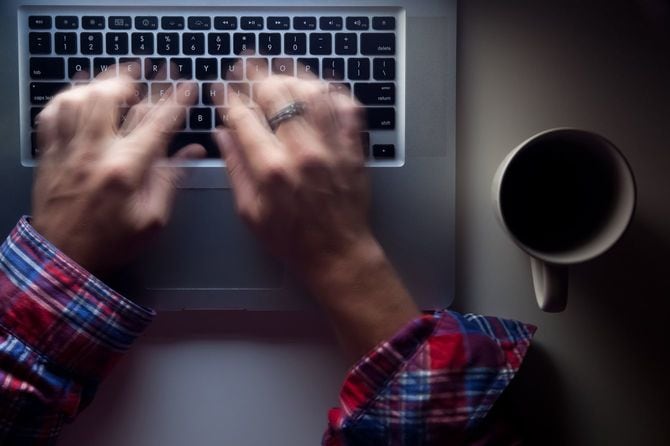 暗い部屋でノートパソコンを使う手元