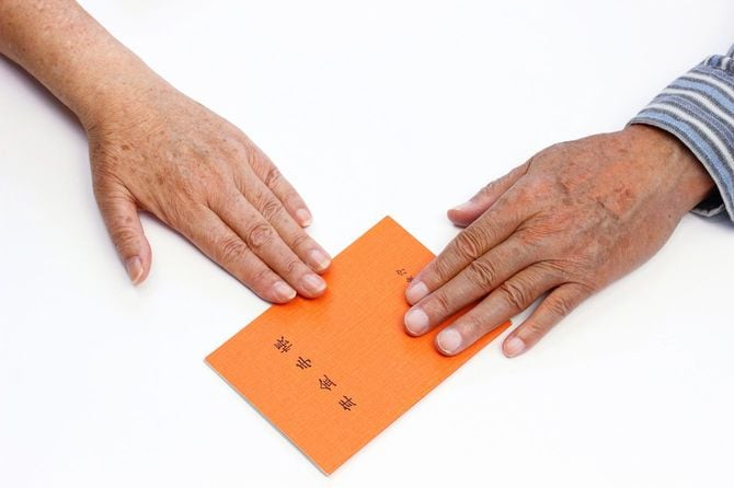 年金手帳と高齢男女の手