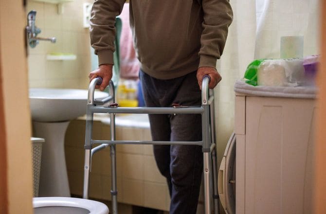 高齢者がトイレで歩行器を持つ姿
