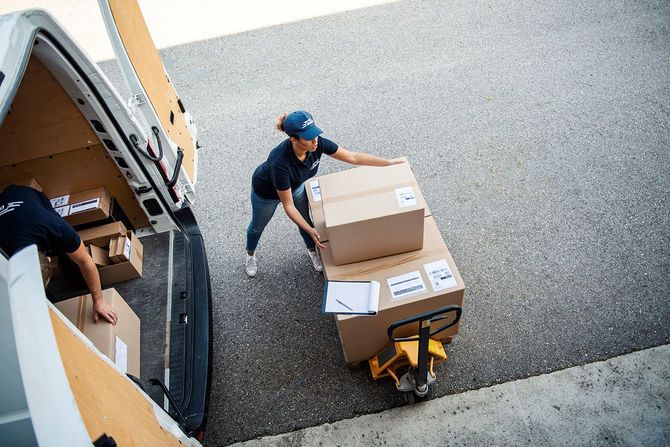 大きな段ボールに入った荷物を運ぶ配達員