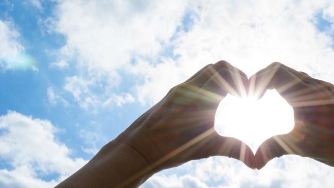 ハートの形をした手の向こうに太陽