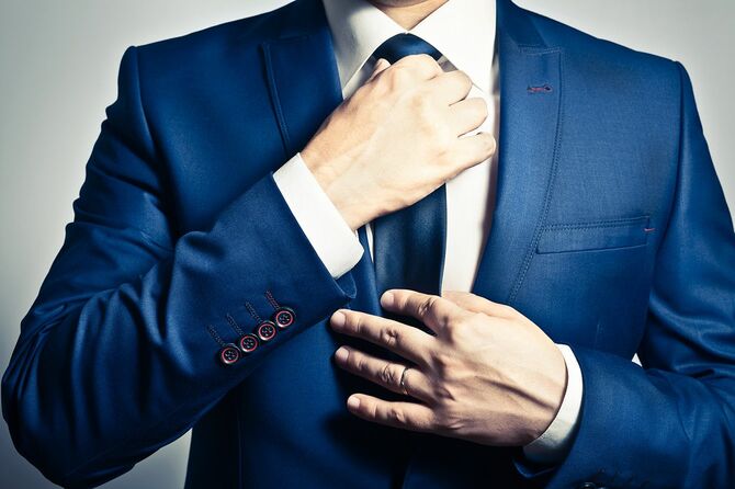 彼のネクタイを調整する青いスーツを着たビジネスマン