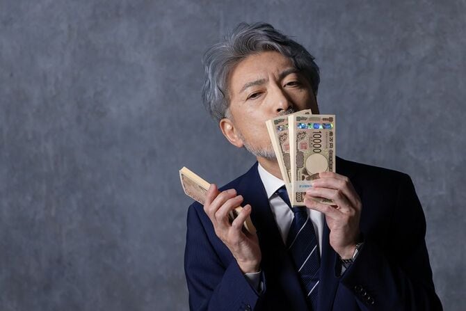 現金の束を手にしたアジアの中年ビジネスマン