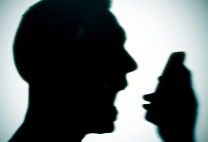 電話に向かって叫ぶ男性のシルエット