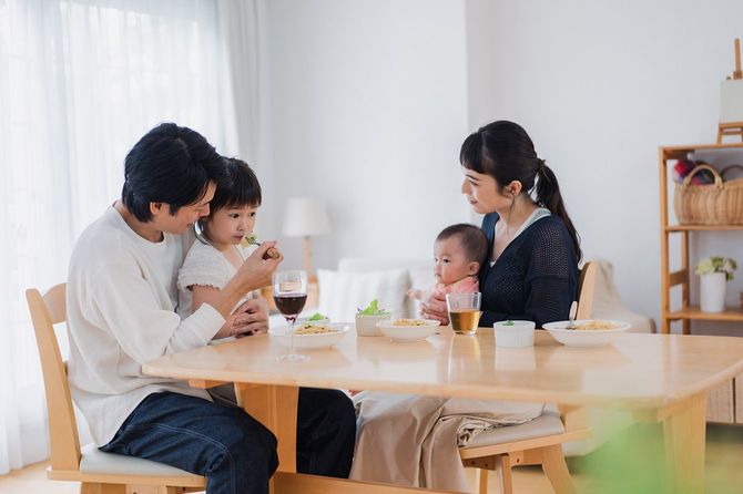 ダイニングで子どもたちにごはんを食べさせる夫婦
