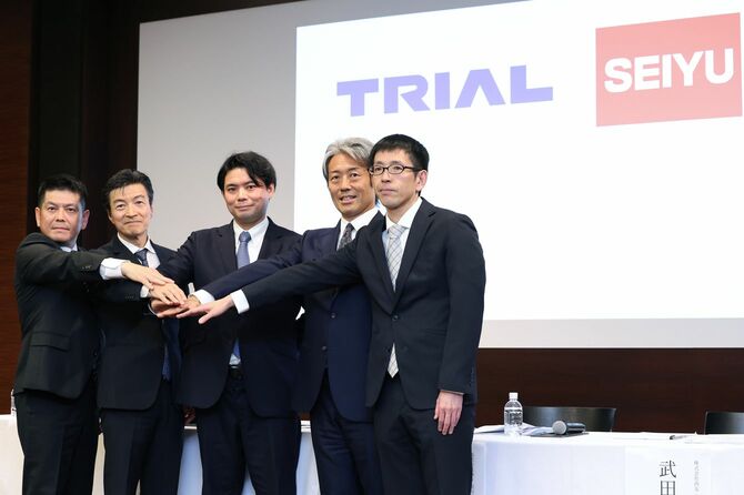 写真撮影に応じるトライアルホールディングス（HD）の亀田晃一社長（左から2人目）と西友の野村優執行役員（右から2人目）ら＝2025年3月5日、東京都千代田区