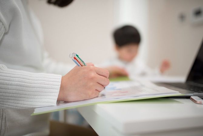子供のそばで在宅ワークをする母親