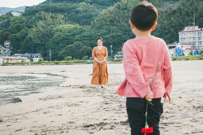 母親にカーネーションの花を手渡す少年
