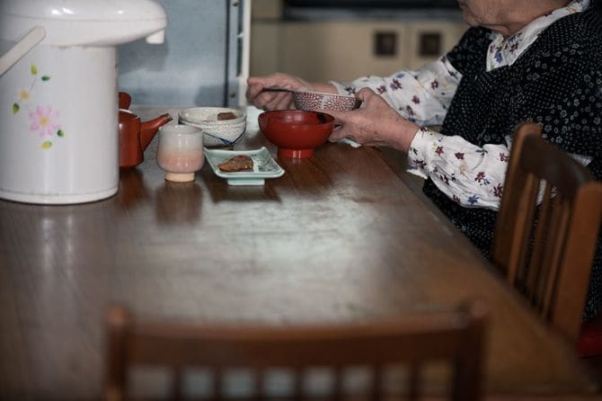 孤独に食事をする年配の日本人女性