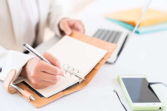 スケジュールブックに記入する女性の手