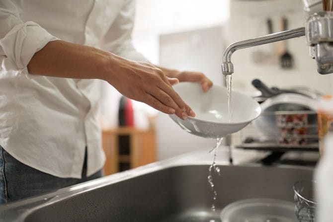 キッチンで洗いものをする男性の手元