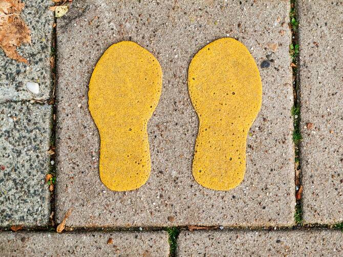 方向の目的のために歩道のタイルに描かれた黄色の靴のプリント