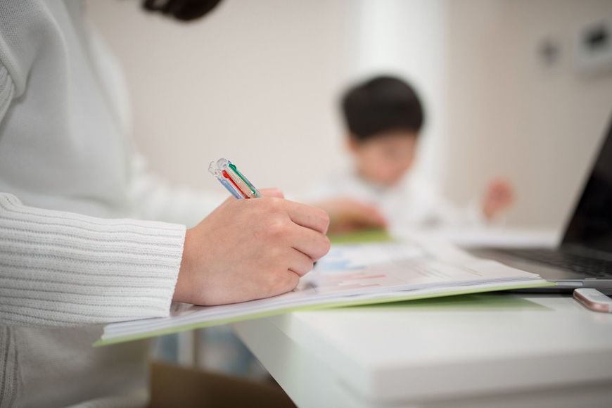 子供のそばで在宅ワークをする母親