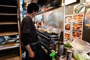 居酒屋で串焼き鶏肉、豚肉、牛肉を焼くシェフ