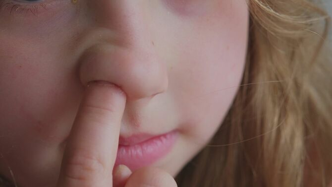 若い白人の女の子は人差し指のフロントで鼻を拾う