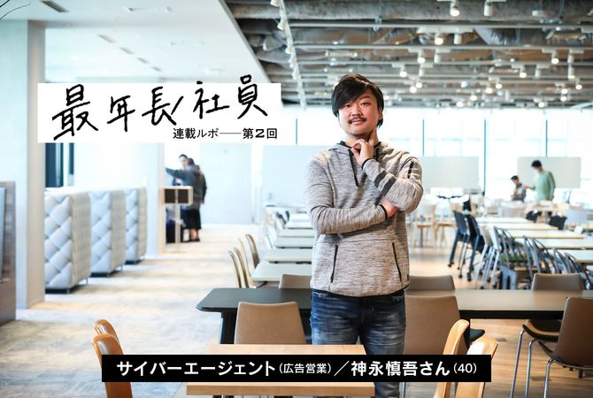 テーブルの奥に腕を組んで立つ男性