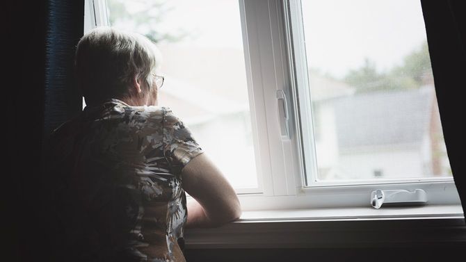 窓を眺めるシニア女性