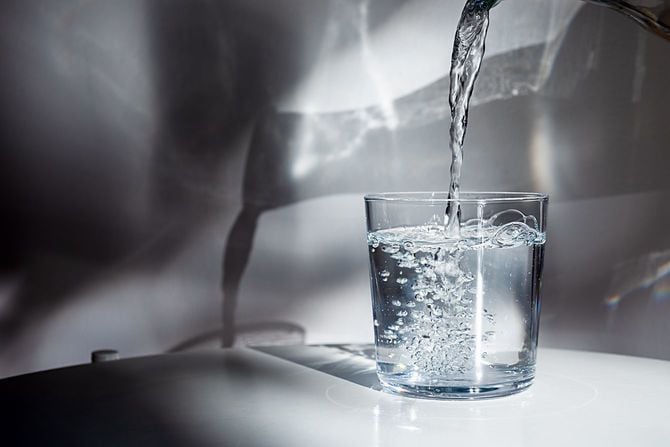 白いテーブルのグラスに飲み水を注ぐ
