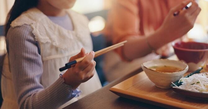 家族と一緒にご飯を食べる少女の手元