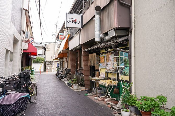 路地裏にある店前の道路は、自転車が行き交い、立ち止まり、店頭の惣菜を見る人が多かった