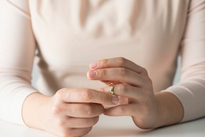 薬指から結婚指輪を外す女性の手元