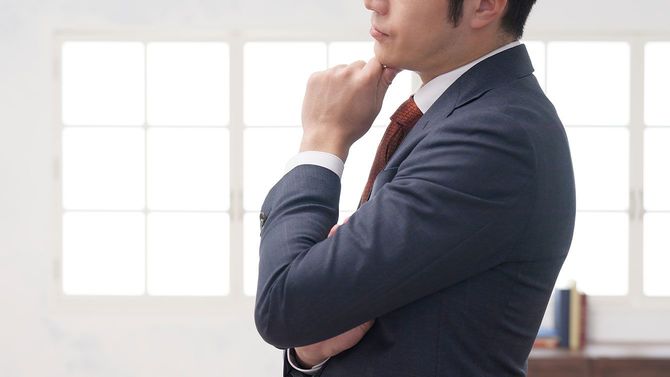 腕を組んで考えているビジネスマン