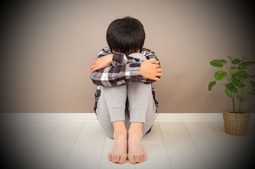 膝を抱えて座っている子供