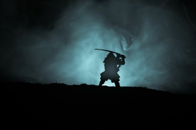 暗く霧が立ち込める中、太刀を構える武士のシルエット