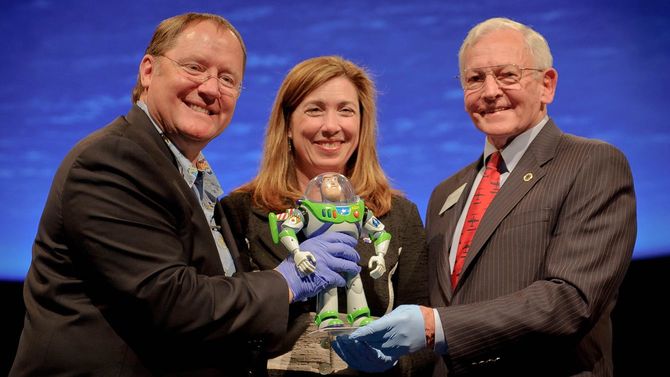 2012年3月29日、ワシントンのスミソニアン国立航空宇宙博物館のギャラリーで、映画『トイ・ストーリー』のジョン・ラセター監督（左）、ローリ・ガーバーNASA副長官、ジョン・デイリー（右）が映画のバズ・ライトイヤーを手にしている。