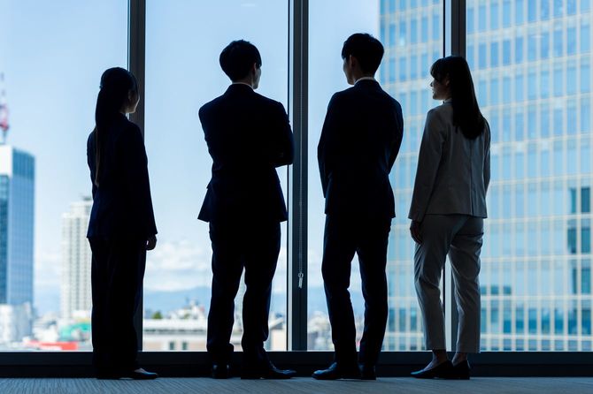 オフィスの窓際に集まり、会話しているグループ