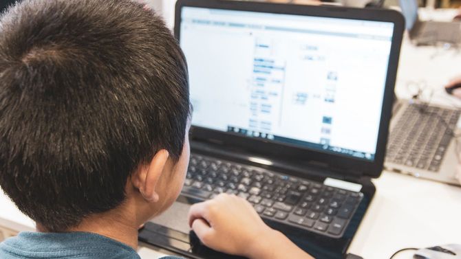 ノートパソコンでプログラミングを学んでいる日本人の少年