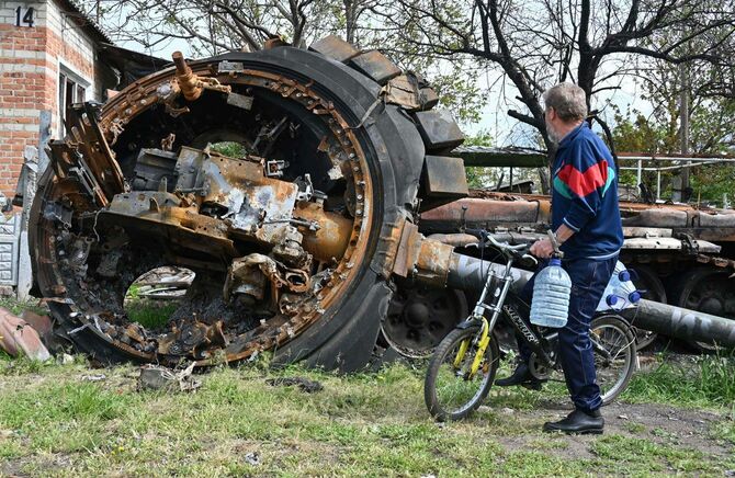 ウクライナ北東部ハリコフ近郊の村で、破壊されたロシア軍の戦車を見る住民（＝2022年05月15日、ウクライナ）