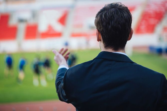 サッカー場で選手に指導するコーチ