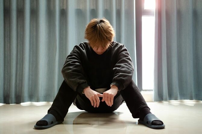 部屋でうつむく若い男性