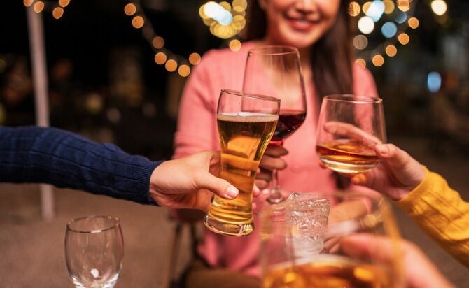 お酒の入ったグラスで乾杯をする人