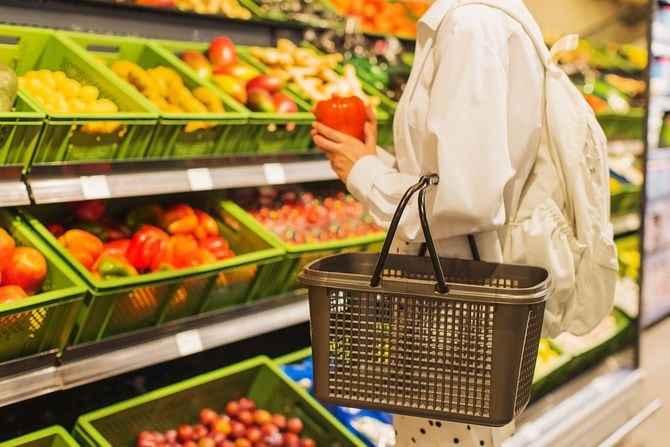 スーパーの野菜売り場で赤いパプリカを手に取る女性