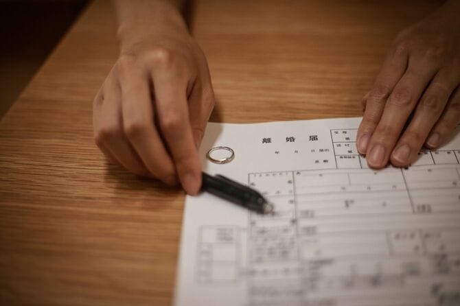 結婚指輪を外した手で離婚届を差し出している手元