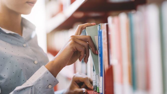 女子学生が書棚から探していた本を取り出そうとしている