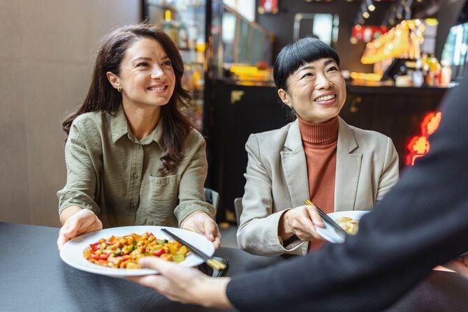 ウェイターから料理を受け取る女性