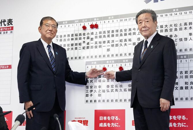 当選を決めた自民党の森山幹事長（右）の名前にバラを付ける総裁の石破首相＝2024年10月27日、東京・永田町の党本部