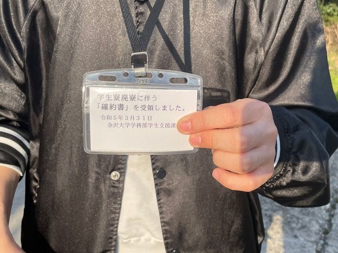 7日間の退去延期を認められた寮生。確約書に応じたことを示す札を首から下げることを大学から求められた。
